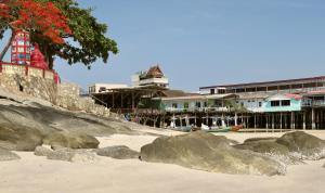 a beach with rocks on the sand and buildings at Fulay Hotel in Hua Hin