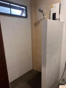 La salle de bains est pourvue d'une douche et d'un mur carrelé blanc. dans l'établissement Baan Yaimai Boutique Samui, à Bophut 