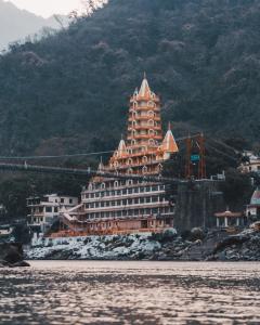 un grand bâtiment sur la rive d'une masse d'eau dans l'établissement Live Free Hostel Rishikesh, à Rishikesh