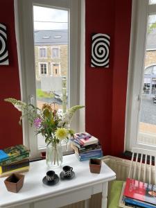 wazon kwiatów na stole obok okna w obiekcie La Reduiste w mieście Redu