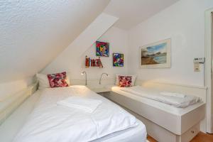 two beds in a room with white walls at Wattblick in Braderup