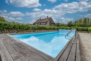 a swimming pool with a bench in front of a house at Wattblick in Braderup