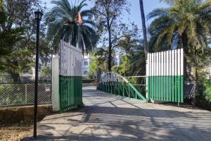 マウント・アブにあるHotel Dada inn Mount abuの椰子の木の並ぶ道の緑と白の門