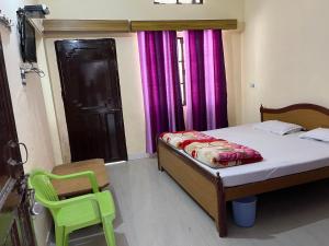 a small bedroom with a bed and a green chair at Hotel Jagat Raj, Sitapur in Sītāpur