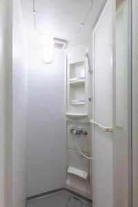 - białą łazienkę z białymi półkami i lodówką w obiekcie Meguro CPMM Musashikoyama Big house w Tokio