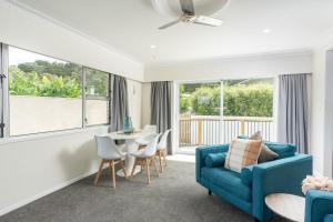 un soggiorno con divano blu, tavolo e sedie di Riverside Retreat a Whangarei