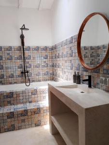 ein Badezimmer mit einem Waschbecken, einem Spiegel und einer Badewanne in der Unterkunft Amara Villa in Gili Trawangan