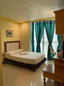 a bedroom with a large bed with blue curtains at Sugarland Suites in Ormoc