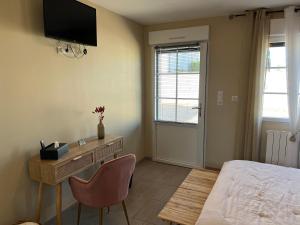 a bedroom with a desk and a bed and a television at La Rose des Vents in Le Crotoy