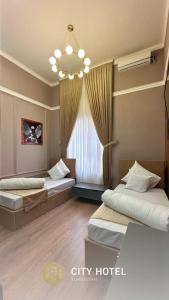 a hotel room with two beds and a chandelier at City Hotel Turkistan in Türkistan +9 photos