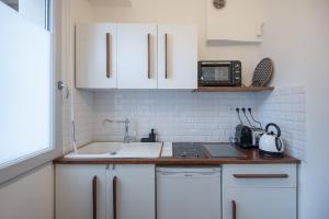 cocina con armarios blancos, fregadero y microondas en Lovely studio near the Old Port en Marsella