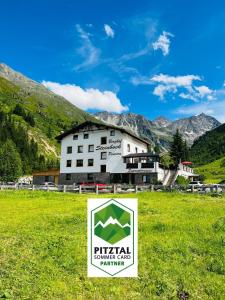 een bord in een veld voor een gebouw bij Apart Berghof Steinbock in Sankt Leonhard im Pitztal