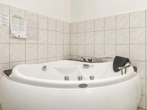 a white bath tub in a white tiled bathroom at 8 person holiday home in V ggerl se in Marielyst