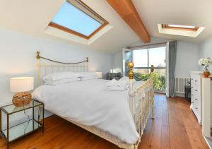 Un dormitorio con una gran cama blanca y una ventana en Pengarth Cottage, en Abersoch