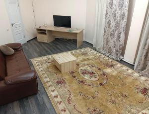 uma sala de estar com um sofá, uma mesa e uma televisão em Merdan Hotel em Zaozërnyy