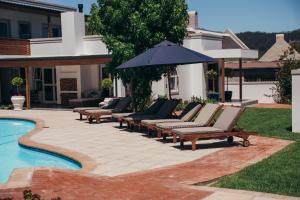 a group of chairs and an umbrella next to a pool at Mirabelle Guesthouse in Franschhoek