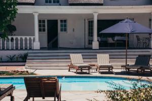 a group of chairs and an umbrella next to a pool at Mirabelle Guesthouse in Franschhoek