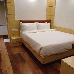 a bed with white sheets and pillows in a room at Hotel Taj Akash in Deoghar