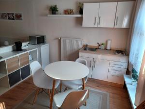 eine kleine Küche mit einem weißen Tisch und Stühlen in der Unterkunft Pension Alte Schmiede in Greifswald