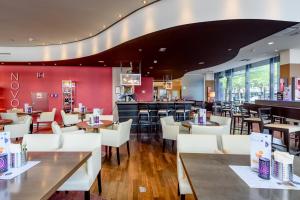 a restaurant with white chairs and tables and a bar at Novotel Aachen City in Aachen
