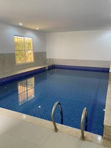 a large swimming pool with two handles in a building at FIG SHADES مزرعة ظلال التين in Ţīwī