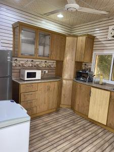 uma cozinha com armários de madeira e um micro-ondas em FIG SHADES مزرعة ظلال التين em Ţīwī
