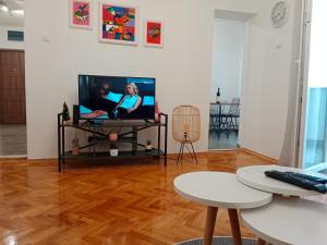 a living room with a tv and a wooden floor at Serenity City Centre in Podgorica