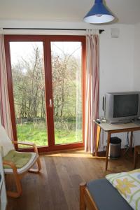 sala de estar con puerta corredera de cristal y TV en Otterstedter Mühle, en Ottersberg