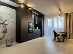 a dining room with a table and a kitchen at BLACK APARTAMENT in Cluj-Napoca