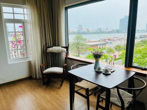 une table et des chaises dans une chambre avec une grande fenêtre dans l'établissement Di Lusso Boutique Riverside Danang Hotel, à Đà Nẵng