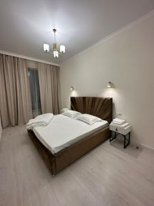 1 dormitorio con 1 cama grande y 1 mesa en 2-комнатные апартаменты в новом жилом комплексе, en Almaty