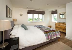 a bedroom with a large white bed and two windows at Morannedd in Abersoch