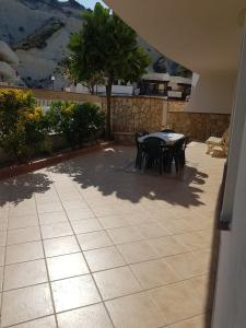 a patio with a table and chairs and a tree at Appartamento Lido Rossello in Realmonte