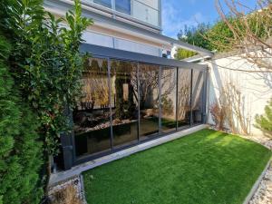 eine Glaserweiterung eines Hauses mit Rasen in der Unterkunft Villapark Pleasure Apartment in Balatonfüred