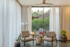 a living room with two chairs and a large window at The Banyan Tree Villa C2 by Stay ALYF, Siolim in Siolim