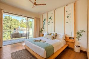a bedroom with a large bed and a large window at The Banyan Tree Villa C2 by Stay ALYF, Siolim in Siolim