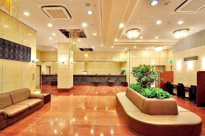 a lobby with couches and plants in a building at Okayama Universal Hotel Annex in Okayama