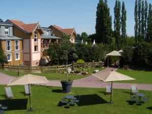 a garden with tables and umbrellas in front of a house at Clos De La Vaupalière - Rouen in La Vaupalière