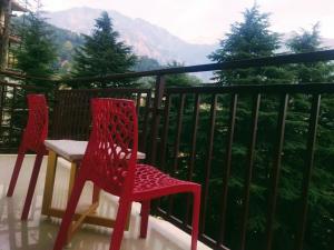 twee rode stoelen en een tafel op een balkon bij Grand Hill mall road Mcleodganj in Dharmsala