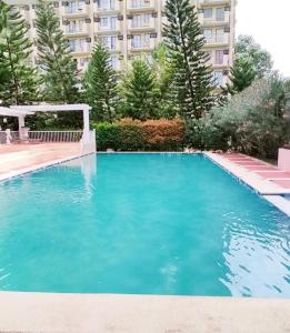 a large blue swimming pool in front of a building at Casi Cozy Spacious Condo For Family, Free Wifi, Netlfix and Pool in Davao City