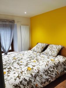 1 dormitorio con cama y pared amarilla en L'Appart en La Chapelle-aux-Bois