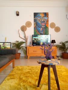 a living room with a television and a painting on the wall at Galerie d'hôte la Martine in Kribi