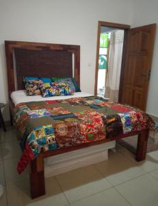 a bed with a quilt on it in a bedroom at Galerie d'hôte la Martine in Kribi