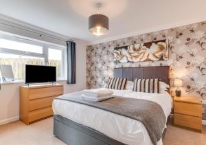 - une chambre avec un grand lit et une télévision à écran plat dans l'établissement Atlantic Breeze, à St Merryn
