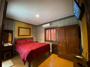 1 dormitorio con cama roja y TV en Djiwanta Cottage by Balkondes Sambirejo, en Groyokan