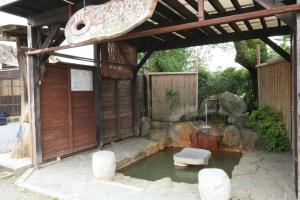 een tuin met een vijver en een houten structuur bij ニュー筑水荘 in Ukiha