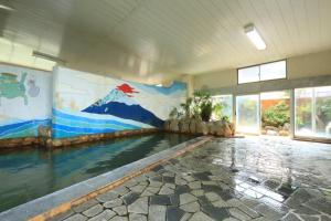 een binnenzwembad met een schilderij aan de muur bij ニュー筑水荘 in Ukiha