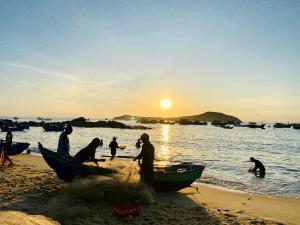 um grupo de pessoas em uma praia com um barco em Kim vàng homestay em Tuy An