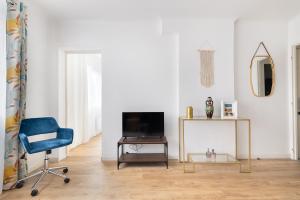 a living room with a tv and a blue chair at Apparemment Cosy Paris CDG Stade Expo in Aulnay-sous-Bois