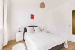 a white bedroom with a large bed with white sheets at Apparemment Cosy Paris CDG Stade Expo in Aulnay-sous-Bois